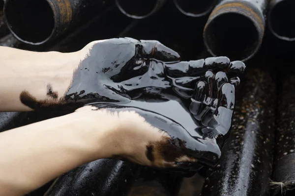 oil leaking. Very dirty hand.Stain hands showing thumbs up with black oil on drill pipes background.