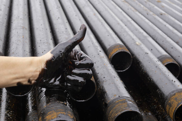 oil leaking. Very dirty hand.Stain hands showing thumbs up with black oil on drill pipes background. hand showing OK