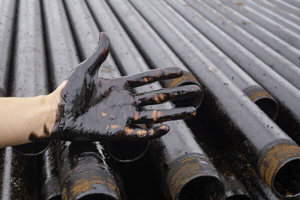 oil leaking. Very dirty hand.Stain hands showing thumbs up with black oil on drill pipes background.