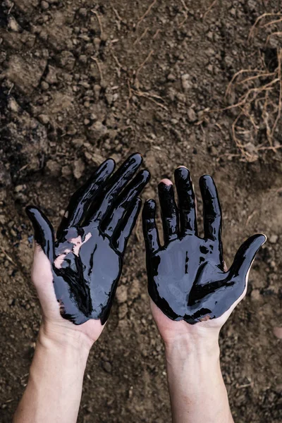 Утечка масла. Очень грязные руки. Ставьте руки, показывающие большие пальцы вверх с мазутом на фоне почвы . — стоковое фото