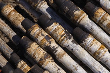 Sondaj borusu. Paslı matkap boruları kuyu bölümünde delindi. Çukur delme kulesi. Petrol ve gaz deposunun açık avlusuna döşenmiş matkap boruları ve boruların kabuğunun görünümü.