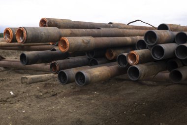 Sondaj borusu. Paslı matkap boruları kuyu bölümünde delindi. Boruyu güverteye döşeyin. Petrol ve gaz deposunun açık avlusuna döşenmiş matkap boruları ve boruların kabuğunun görünümü.