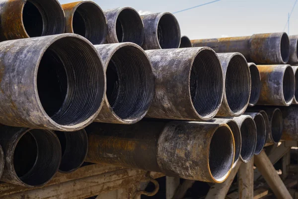 Tuyau de forage. Des tuyaux de forage rouillés ont été forés dans la section du puits. Appareil de forage. Vue de la coquille des tuyaux de forage et des tuyaux posés dans la cour ouverte de l'entrepôt de pétrole et de gaz . — Photo