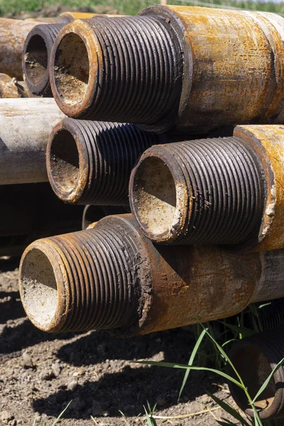 Oil Drill pipe. Rusty drill pipes were drilled in the well section. Downhole drilling rig. Laying the pipe on the deck. View of the shell of drill pipes laid in courtyard of the oil and gas warehouse — Stock Photo, Image