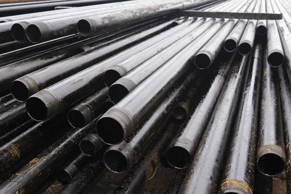 Oil Drill pipe. Rusty drill pipes were drilled in the well section. Downhole drilling rig. Laying the pipe on the deck. View of the shell of drill pipes laid in courtyard of the oil and gas warehouse — Stock Photo, Image