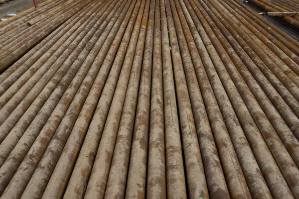 Oil Drill pipe. Rusty drill pipes were drilled in the well section. Downhole drilling rig. Laying the pipe on the deck. View of the shell of drill pipes laid in courtyard of the oil and gas warehouse — Stock Photo, Image