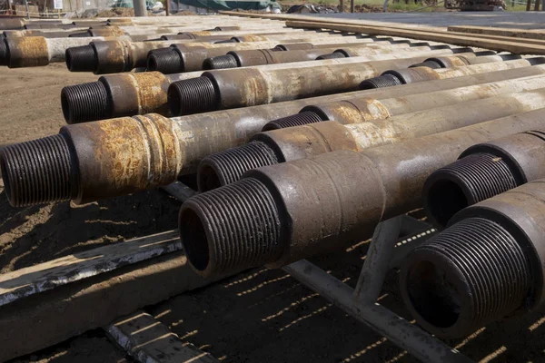 Tubo di trivella. Tubi di perforazione arrugginiti sono stati perforati nella sezione del pozzo. Impianto di perforazione. Posa il tubo sul ponte. Vista del guscio di tubi di perforazione prevista nel cortile del magazzino di petrolio e gas. — Foto Stock