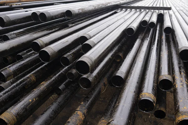 Oil Drill pipe. Rusty drill pipes were drilled in the well section. Downhole drilling rig. Laying the pipe on the deck. View of the shell of drill pipes laid in courtyard of the oil and gas warehouse. — Stock Photo, Image