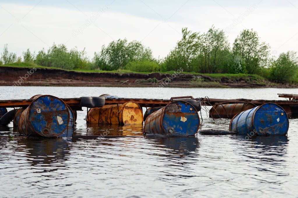 dumped oil drums cause pollution in the water, more and more the water is polluted by throwing away waste which therefore gets into the rivers. Polluted river full of various garbage