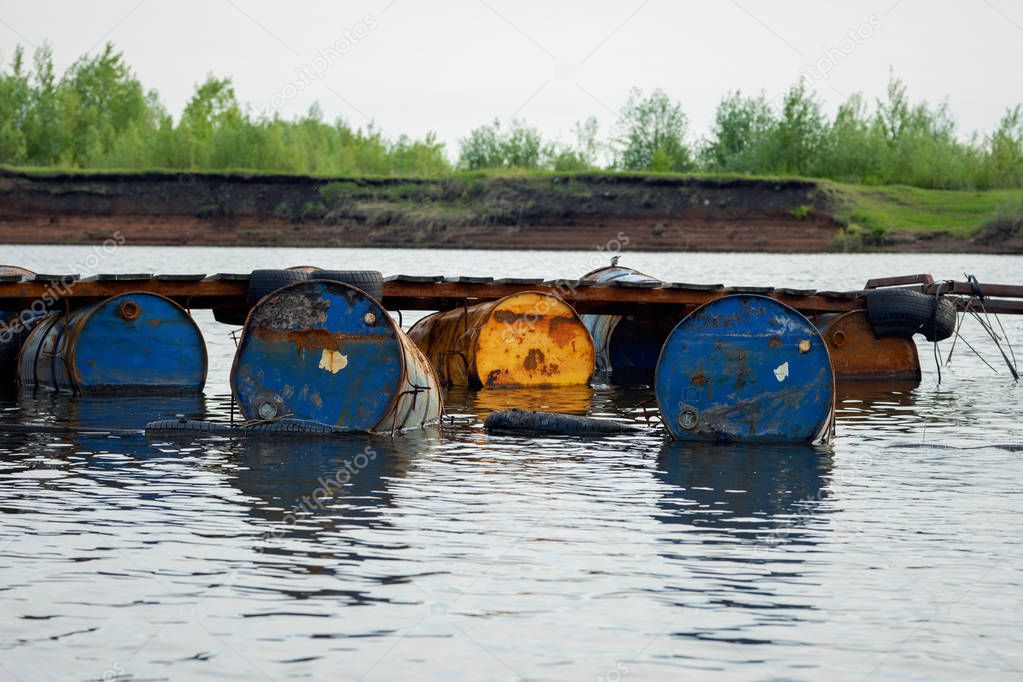 dumped oil drums cause pollution in the water, more and more the water is polluted by throwing away waste which therefore gets into the rivers. Polluted river full of various garbage