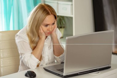 Sıkılmış genç kadın evde ofis masasında oturup dizüstü bilgisayarda çalışamayan uzaktan bakın, yorgun kız öğrenci çalışma isteği duymadan, dikkati dağılmış bir şekilde çalışmaya başladı. Donuk monoton iş konsepti.