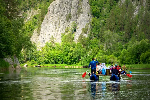 Grupa przyjaciół w nadmuchiwanym tratwie, która porusza się w dół rzeki. Górski krajobraz wody rzeki. — Zdjęcie stockowe