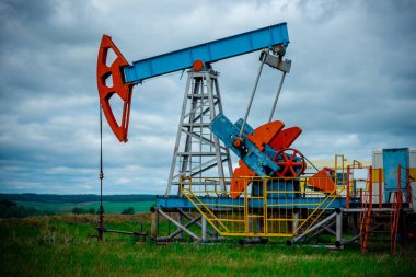 Pompa jakı ile petrol sahası, beyaz bulutlar ile mavi gökyüzü profilli, ilkbaharda güneşli bir günde