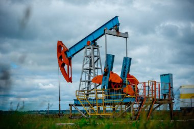Pompa jakı ile petrol sahası, beyaz bulutlar ile mavi gökyüzü profilli, ilkbaharda güneşli bir günde