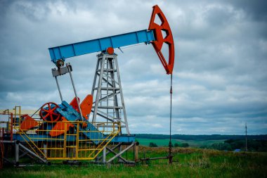 Pompa jakı ile petrol sahası, beyaz bulutlar ile mavi gökyüzü profilli, ilkbaharda güneşli bir günde