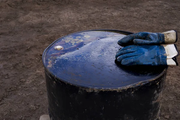 Dirty work gloves on rusty barrel. Gloves sitting on top of a whiskey barrel inside of oil