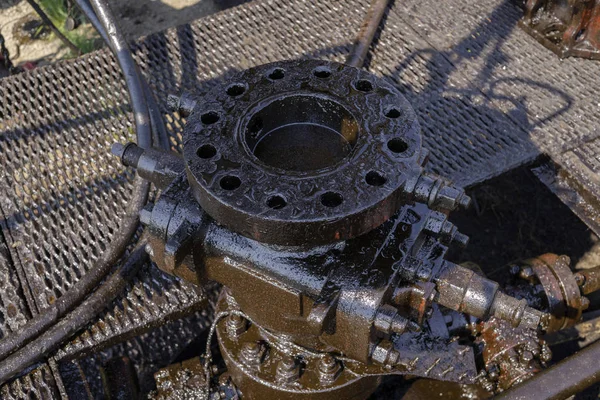 Oil well and small crude lake at the well head in Fang oil field, crude oil from oil well with reflex of pumpjack. blowout preventer device with flanges on the oil rig