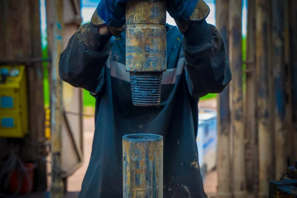 Offshore petrol kuyusu işçisi kuyu başındaki petrol kuyusunda delik açmak için alet ve ekipman hazırlayın. Sondaj borusu bağlantısı kuruyorum. Tribünlerin arasından matkap borusu bağlantısı için bir görünüm