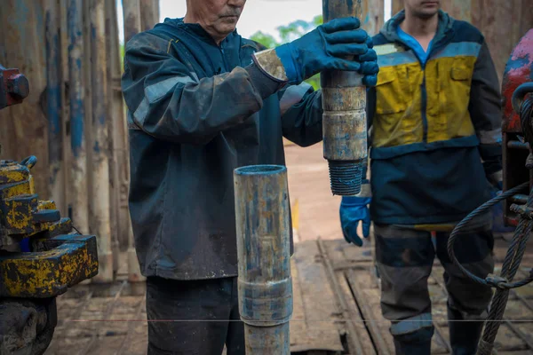 Offshore oljerigg arbetare förbereda verktyg och utrustning för perforering olja och gas brunn på wellhead plattform. Göra upp en borrrörsanslutning. Utsikt för anslutning av borrör mellan läktaren. — Stockfoto