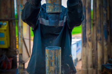 Offshore petrol kuyusu işçisi kuyu başındaki petrol kuyusunda delik açmak için alet ve ekipman hazırlayın. Sondaj borusu bağlantısı kuruyorum. Tribünlerin arasından matkap borusu bağlantısı için bir görünüm.