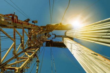 Petrol ve gaz endüstrisinde kara teçhizatı. Bulutlar ile mavi bir gökyüzüne karşı petrol sondaj kulesi.