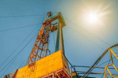 Petrol ve gaz endüstrisinde kara teçhizatı. Bulutlar ile mavi bir gökyüzüne karşı petrol sondaj kulesi.