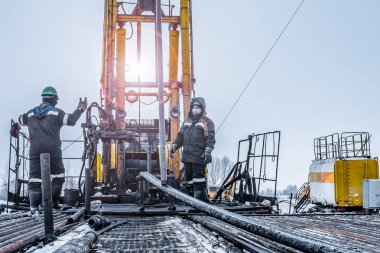 Offshore petrol kuyusu işçisi kuyu başındaki petrol kuyusunda delik açmak için alet ve ekipman hazırlayın. Sondaj borusu bağlantısı kuruyorum. Tribünlerin arasından matkap borusu bağlantısı için bir görünüm