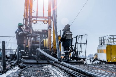 Offshore petrol kuyusu işçisi kuyu başındaki petrol kuyusunda delik açmak için alet ve ekipman hazırlayın. Sondaj borusu bağlantısı kuruyorum. Tribünlerin arasından matkap borusu bağlantısı için bir görünüm