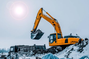 Kazı makinesi kazıları kamyona yüklüyor. Kazı makineleri ağır inşaat ekipmanlarıdır. Dönen platformda bir boom, dipper veya stick, kova ve taksiden oluşur..