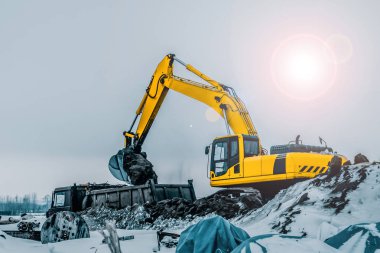 Kazı makinesi kazıları kamyona yüklüyor. Kazı makineleri ağır inşaat ekipmanlarıdır. Dönen platformda bir boom, dipper veya stick, kova ve taksiden oluşur..