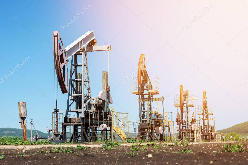 Oil pump jack rocking with pipeline in the background. Rocking machines for power generation. Extraction of oil.