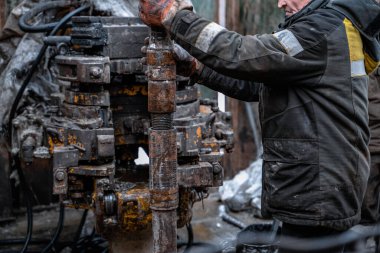 Üniformalı, kask ve gözlüklü iki matkap, sondaj kuyusundan çıkardıktan sonra sondaj borularını yerleştiriyor. Çalışan insan kavramı