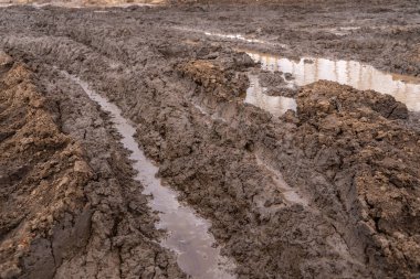 Yaz günü etrafı yeşil ormanlarla çevrili çamurlu ve çamurlu berbat toprak yolda arabanın görüntüsü. Rusya 'da kirli kırsal yol