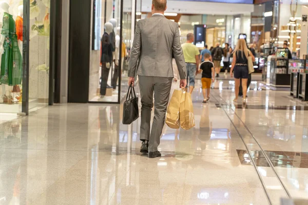 若い男のショッピングモールで彼の手に多くのショッピングバッグ. — ストック写真