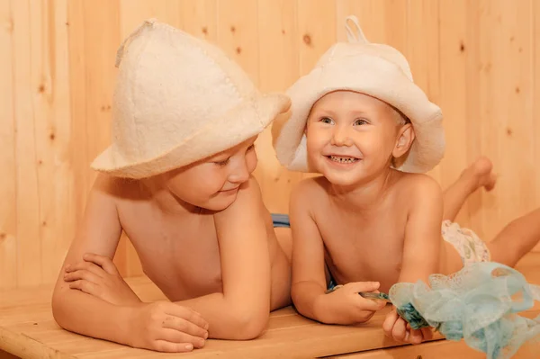 Beauty, healthcare. baby Boy relaxing in the sauna Toddler with broom and  hat in russian sauna or bath Stock Photo