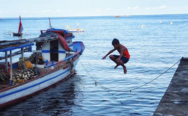 Tomohon, Kuzey Sulawesi, Endonezya - Ekim 05: oynama ve iskeleden denize Tomohon, Sulawesi, Endonezya atlama çocuk