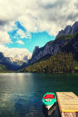 Güzel Gosausee gölü manzarası Dachstein dağları, tekne, orman, bulutlar ve Avusturya Alpleri 'ndeki sularda yansımalar. Salzkammergut bölgesi.