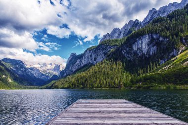 Güzel Gosausee gölü manzarası Dachstein dağları, tekne, orman, bulutlar ve Avusturya Alpleri 'ndeki sularda yansımalar. Salzkammergut bölgesi.