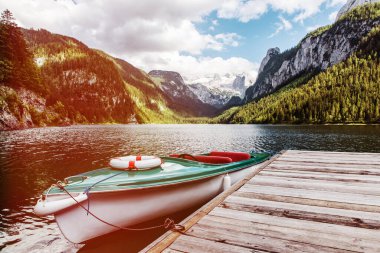 Güzel Gosausee gölü manzarası Dachstein dağları, tekne, orman, bulutlar ve Avusturya Alpleri 'ndeki sularda yansımalar. Salzkammergut bölgesi.