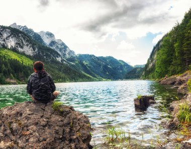 Avusturya 'nın yukarısındaki güzel Gosausee gölüne bakan genç bir çocuk..