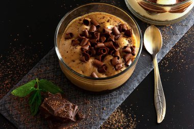 Mokachchino tatlı siyah çikolata parçaları, rendelenmiş çikolata ve siyah arka plan üzerinde taze nane süslenmiş. 