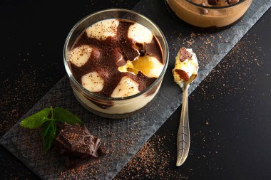 Cheesecake tatlı koyu çikolata parçaları, rendelenmiş çikolata ve taze nane siyah ile dekore.