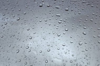 Gri arka planda su damlaları, yakın çekim. Cam yüzeyinde soyut gri doku