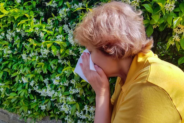 Adult woman is going to sneeze. Pollen allergy concept. Flowering trees in background