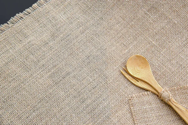 Set of wooden bamboo cutlery: fork and spoon on sackcloth background, copy space. Flat lay