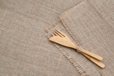 Ahşap bambu çatal seti: çatal ve bıçak çuval bezi arka plan üzerinde kopya alanı ile. Düz yatıyordu