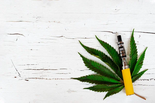 Marijuana/cannabis Leaf med elektronisk cigarett på trä bakgrund, kopiera utrymme. Flat Lay — Stockfoto