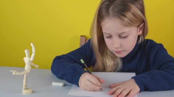 Gadis Kaukasia kecil yang menawan menggambar seorang pria kayu — Stok Video
