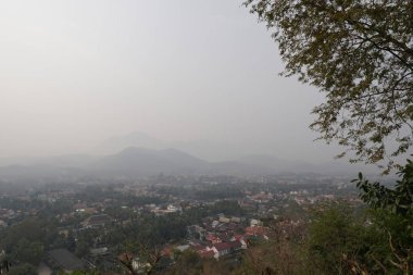 bulutlu bir günde yeşil ağaçlar ve evler ile tepelerin havadan görünümü