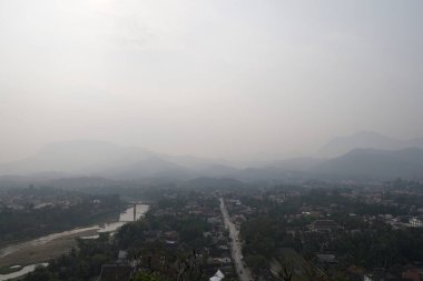 bulutlu bir günde yeşil ağaçlar ve evler ile tepelerin havadan görünümü